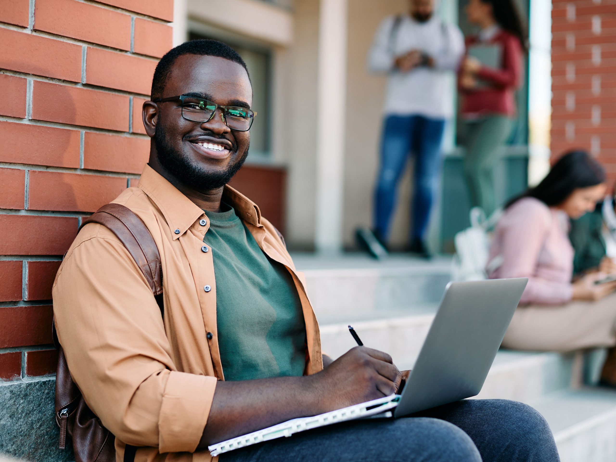 Student on computer on campus steps