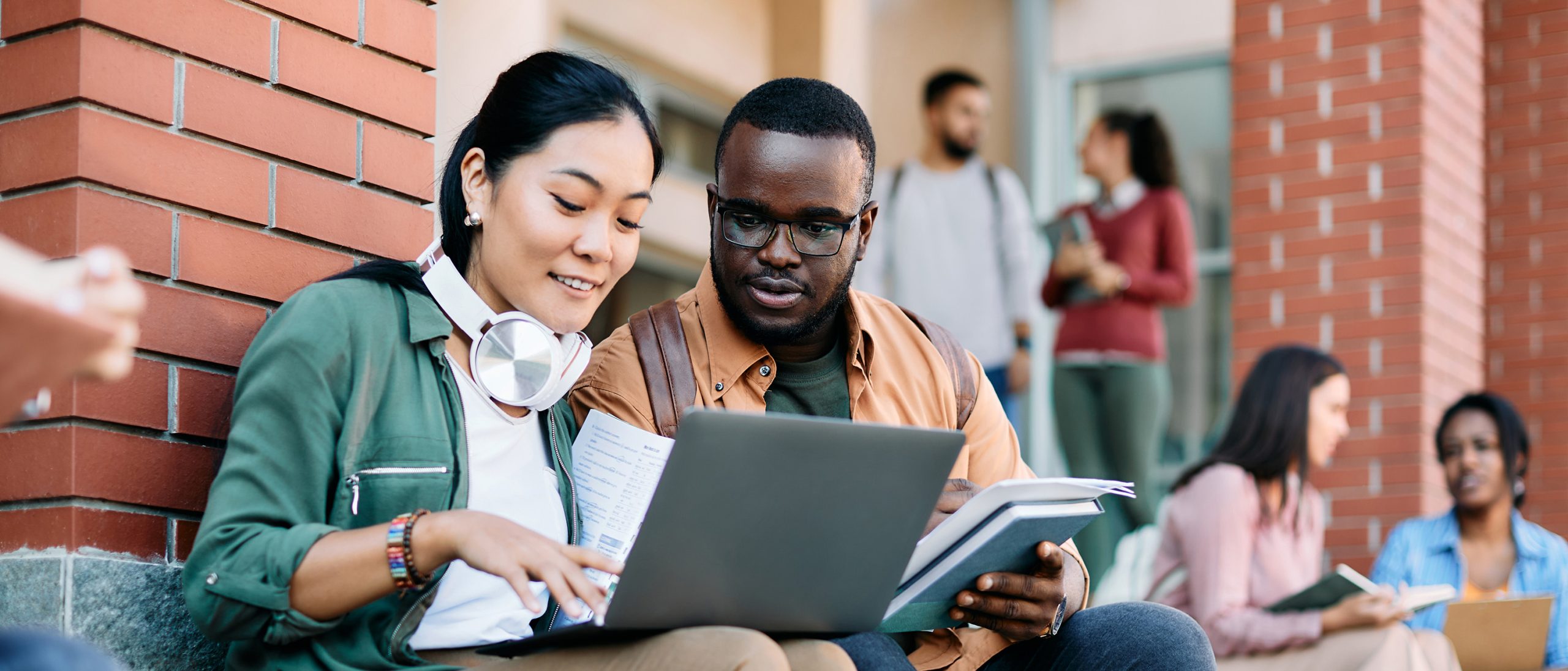 College students looking at computer on campus