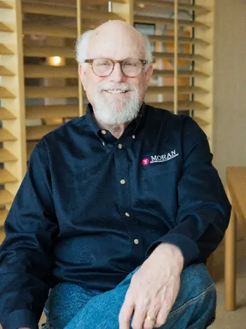 A photo of Moran's founder, Charlie Moran, in a black shirt with the original Moran Technology Consulting logo.